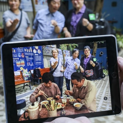 Japanese artist Masaki Fujihata is flanked by two Wan Chai residents as they try out his augmented reality project. Photo: Dickson Lee