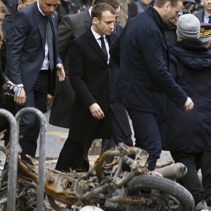 French President Emmanuel Macron walks past a torched motorbike near the Champs Elysee in Paris, France on December 2, 2018. Photo: EPA