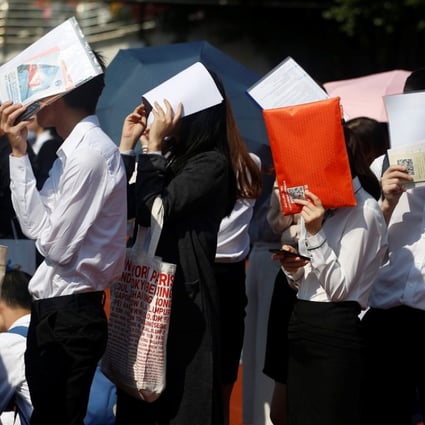 Students shield themselves from the sun as they line up at a job fair at a Guangzhou university last week. There are signs that China’s jobs market is weakening. Photo: Reuters