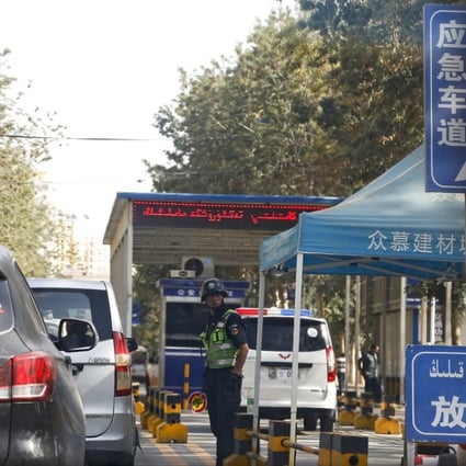 A policeman stands watch as vehicles drive past a checkpoint in Hotan, in western China's Xinjiang region. Photo: AP