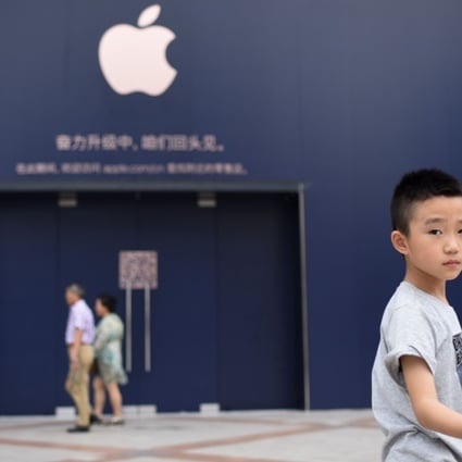 A boy holds a Chinese flag as he walks past an Apple Store undergoing renovation in Beijing on July 18, 2018. Photo: AFP