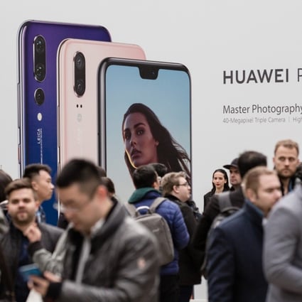 Attendees stand in front of Huawei Technologies Co. signage during the company's P20 Pro smartphone unveiling event in Paris, France, on Tuesday, March 27, 2018. Photo: Bloomberg