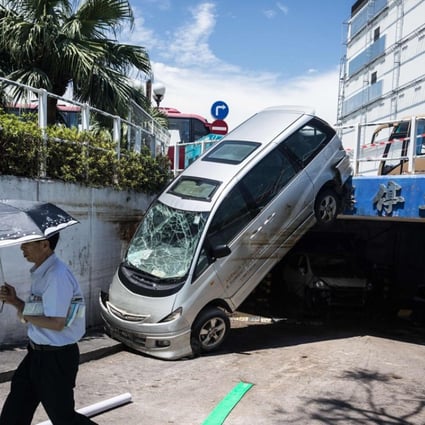 A man walking past a damaged car in the aftermath of Typhoon Hato in Macau on August 26, 2017. Photo: AFP