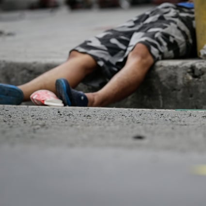 Evidence markers surround the body of a dead man shot in Makati, south of Manila. Photo: EPA