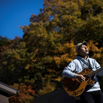 Japanese musician Kyochi Watanabe plays his guitar at the entrance of Aokigahara Forest in Narusawa village. Photo: AFP