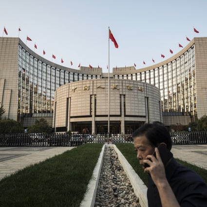 A man talks on a mobile phone outside the People's Bank of China headquarters in Beijing, China. China's central bank is said to have gauged demand for 63-day reverse repurchase agreements for the first time ever. Photo: Bloomberg