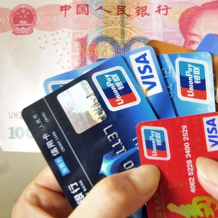A Chinese woman poses with a handful of credit cards and a 100 yuan banknote Beijing . Photo: AFP