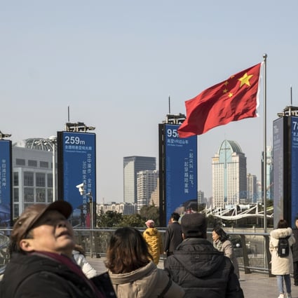 Pedestrians walk past a Chinese national flag on an elevated walkway in Shanghai, China, on December 28, 2018. Photo: Bloomberg