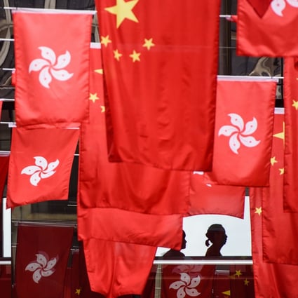 People walk past a display of China’s national flags and those of Hong Kong, ahead of the 20th anniversary of the city's handover from Britain to China. Photo: AFP