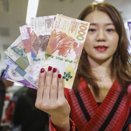 Model poses with new and old banknotes for Lunar New Year red packets at the HSBC branch in Mong Kok. Photo: Tory Ho
