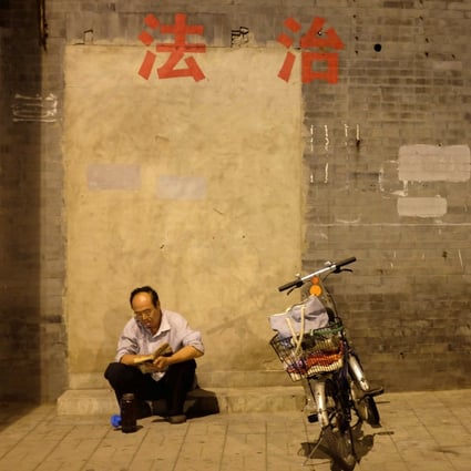 A man reads a book below political slogans reading “rule of law” and “harmony” in central Beijing. The education ministry has launched a review of all university constitutional law textbooks. Photo: Reuters