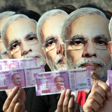 Girls wearing Modi masks hold up replacement Indian rupees following 2016’s demonetisation. Photo: EPA