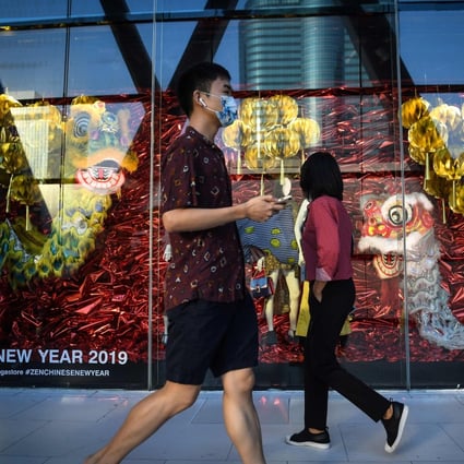 Chinese tourists walk past a Lunar New Year-themed display at a shopping centre in Bangkok, Thailand, on February 5, 2019. Photo: Agence France-Presse