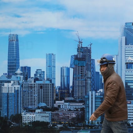 A Chinese migrant worker walks past a poster placed outside of a construction site showing the design of future high-raise buildings and skyscrapers in the central business district in Beijing. Photo: EPA