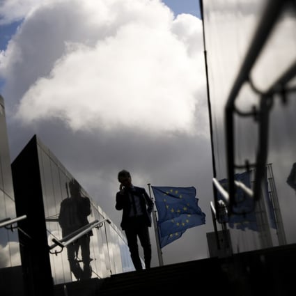 A man walks past European Union flags outside the European Commission headquarters in Brussels. Photo: AP Photo