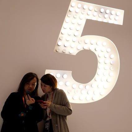 Visitors use their smartphones as they stand next to a 5G panel inside a booth at the annual industry trade show MWC Barcelona, held in the Spanish city from February 25 to 28, 2019. Photo: Reuters