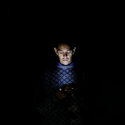 A man looks at his mobile phone during the blackout in Caracas, Venezuela. Photo: Reuters