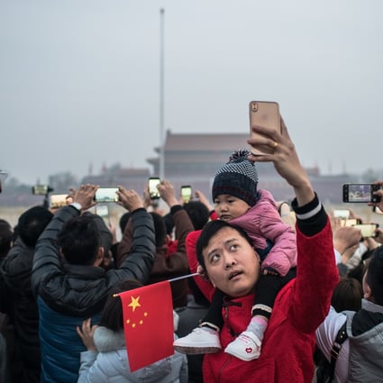 A Chinese man takes a photo with a child as they wait for the Chinese flag rising ceremony at Tiananmen Square before the opening of the second session of the 13th National People's Congress (NPC) at the Great Hall of the People in Beijing. Photo: EPA