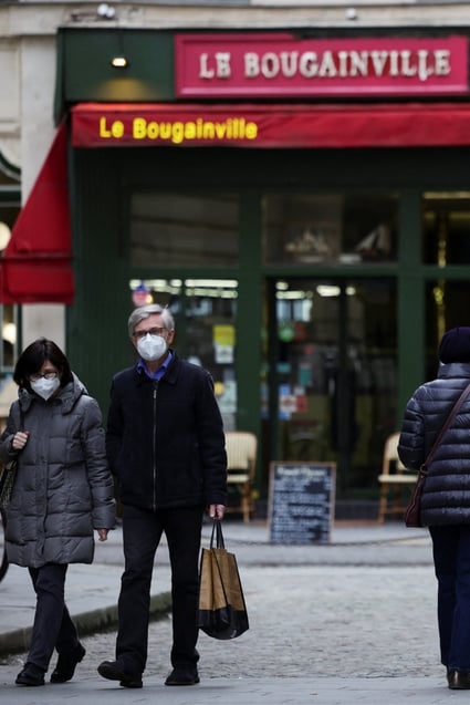 People wear protective face masks as they walk along a street in Paris, France. Photo: Reuters