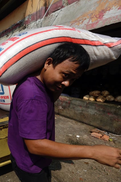 A worker carries a sack of rice at a market in Depok, Indonesia as the government imports 300,000 tons of rice in anticipation of the potential decline in agricultural land production. Photo: EPA-EFE