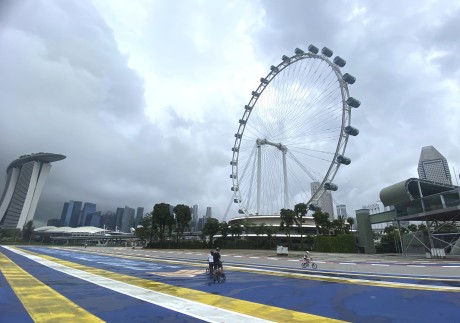 Cyclists pass the Singapore Flyer Ferris Wheel attraction. Photo: AP