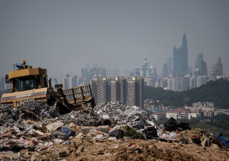 This picture taken on March 6, 2013 shows a landfill in the new territories of Hong Kong as the Chinese city of Shenzhen looms in the background.  Official data shows that the city generates about 19,000 tonnes of solid waste every day, with 9,100 tonnes dumped into landfills -- two thirds of it domestic waste. Only 52 percent of total waste is recycled in a city that produces an average of 921 kilograms of rubbish per person per year, which is more than twice the amount compared to Japan (410kg) and South Korea (380kg), according to the Organisation for Economic Cooperation and Development.  AFP PHOTO / Philippe Lopez (Photo by Philippe LOPEZ / AFP)