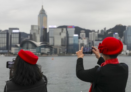 People take photographs on an overcast day at the Tsim Sha Tsui waterfront on December 16. The city has been grappling with a sluggish economic recovery, weak consumption and falling stock and property markets. Photo: Xiaomei Chen