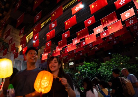 People walk past the Chinese national and Hong Kong flags on October 1, 2023. PhotoL EPA-EFE
