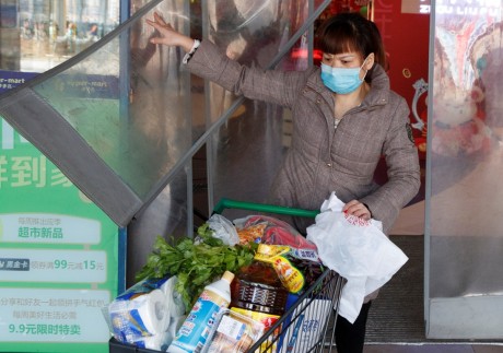 A woman wearing a face mask leaves a supermarket with a loaded shopping trolley in Changsha in China’s Hunan province on January 29. China’s market regulator has vowed to punish businesses engaging in price-gouging. Photo: Reuters