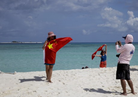 Chinese tourists take souvenir photos with the national flag on Quanfu, one of the Paracel Islands, in Sansha prefecture of Hainan province in the South China Sea, in September 2014. Photo: AP