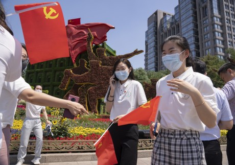 Communist Party members hold party flags in front of a floral decoration for the upcoming 100th anniversary of the founding of China's ruling Communist Party in Beijing. Photo: AP Photo