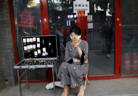 A woman tries to sell jewellery in front of a closed shop in Beijing. China’s smallest businesses and the self-employed have been hit especially hard as retail consumption has taken a big hit. Photo: Reuters