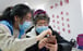 A student volunteer from Beijing Foreign Studies University teaches as a senior resident learns how to use a health-tracking app, introduced amid the COVID-19 outbreak. Photo: Xinhua